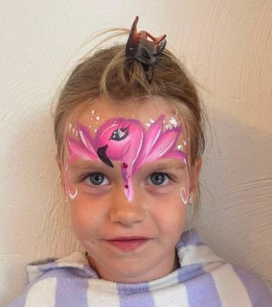 Meisje met roze flamingo-schmink op het voorhoofd en glittersteentjes op de neusbrug